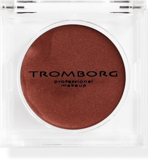 A round, reddish-brown makeup product in clear plastic packaging with black text reading Tromborg.
