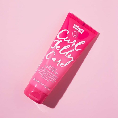En ljusrosa tub med Curl Jelly Cave-balsam på en rosa bakgrund.