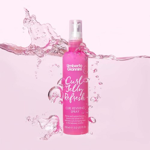 Rosa sprayflaska märkt 'Curl Jelly Refresh' med vattenstänker runt den.