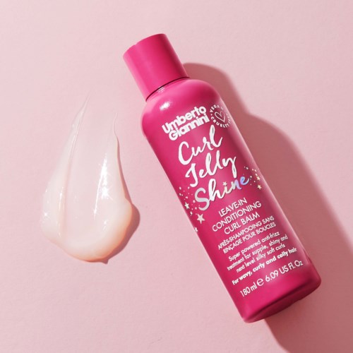Pink flaska av Umberto Giannini Curl Jelly Shine med lite gelé bredvid på rosa bakgrund.