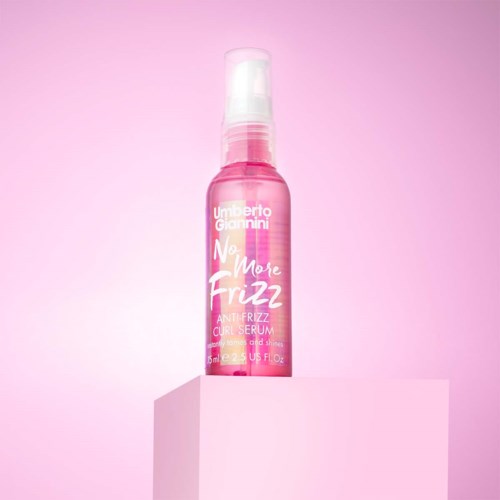 Rosa sprayflaska märkt 'No More Frizz' på en ljusrosa bakgrund.