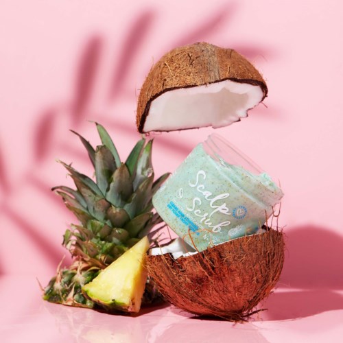 A coconut and pineapple with ice cream inside, on a pink background, creating a tropical dessert scene.