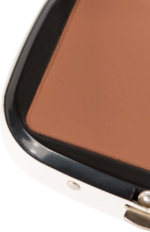 Close-up of a makeup compact with brown powder inside and a silver edge frame.