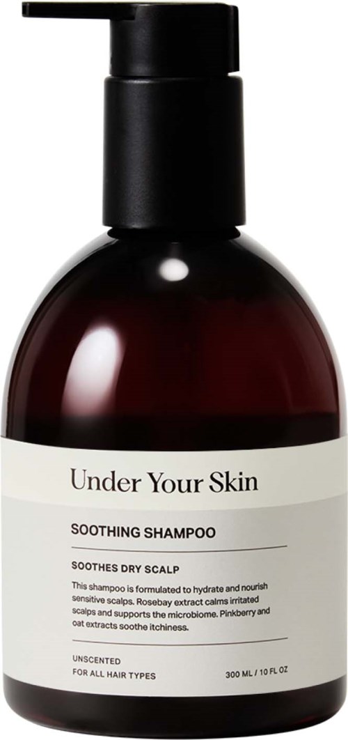 En mörkröd schampoflaska med svart pump, märkt "Under Your Skin" lugnande schampo för torr hårbotten.