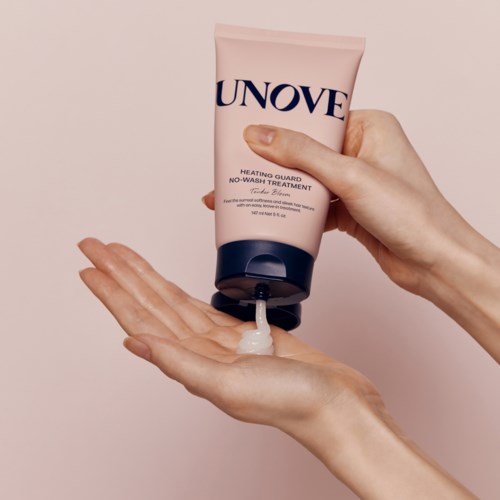 Iemand giet een lichte roze crème uit een tube met 'UNOVE' erop in hun handpalm.