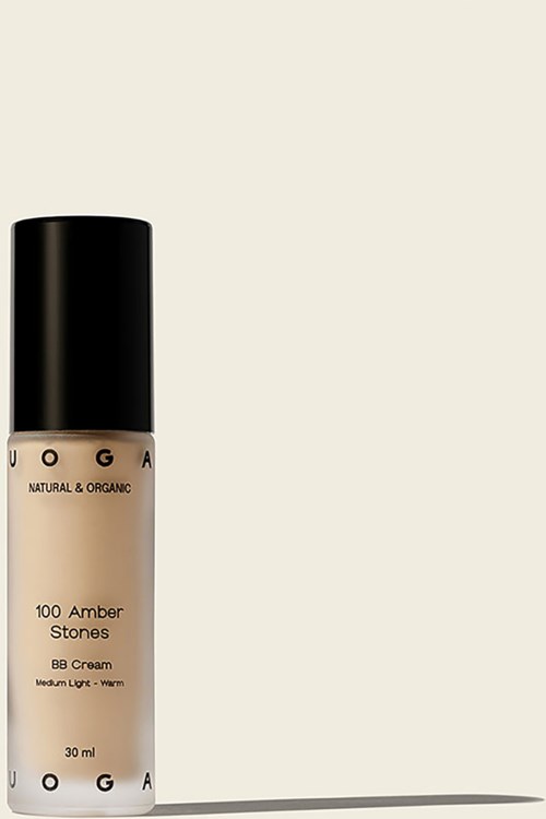 A bottle of foundation with a black cap, beige liquid inside, labeled 'UOGA' and 'Amber Stones'.