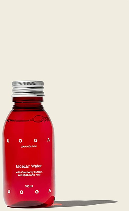 En lille rød flaske med sølvstop mærket 'Micellar Water' og 'UOGA' til hudpleje.