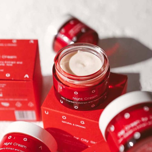 Red jars and boxes of night cream with white caps, some open showing cream inside.