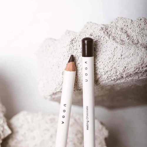 Two white pens, one with a black cap and the other with a wooden tip, stand against a textured rock wall.