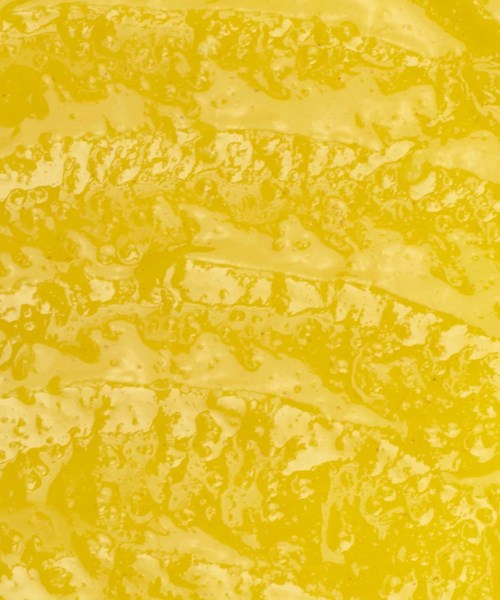 A close-up of a yellow, textured food surface, possibly cheese or a similar item.
