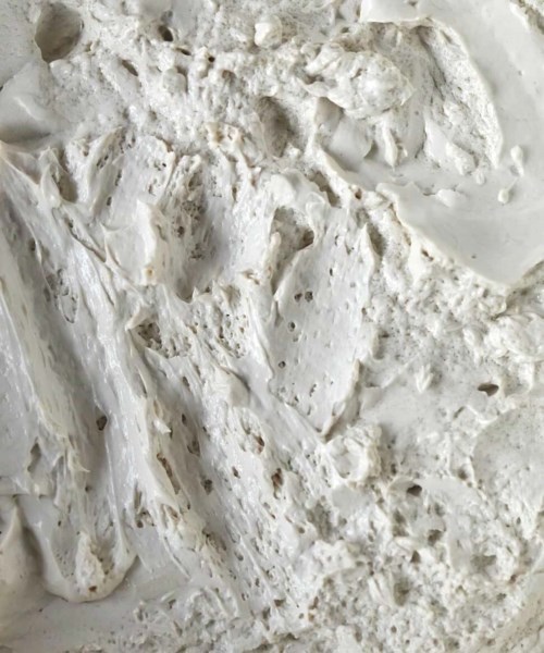 A rough, white, textured surface with irregular bumps and lines.