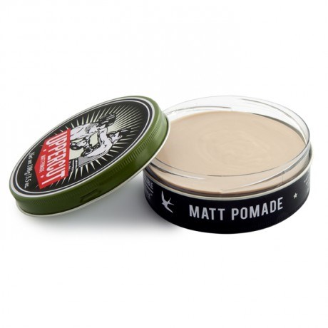 En rund beholder med matt pomade, med svart-hvitt etikett og grønt lokk ved siden av.