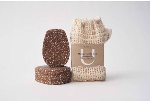 To brune såper med hvite prikker og en beige loofah på en hvit bakgrunn.