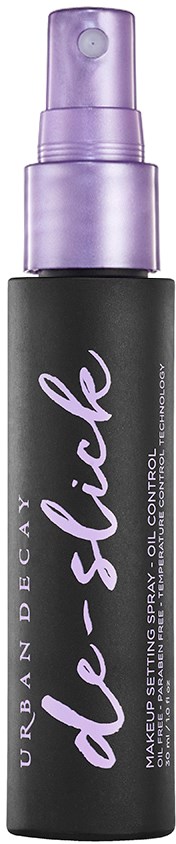 Musta pullo violetilla suihkukaulalla, etiketissä 'Urban Decay de-slick,' öljynhallintaan ja meikin kiinnitykseen.