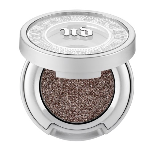 Een kleine ronde make-up container met een glanzende, glittersachtige bruine oogschaduw en een witte deksel.