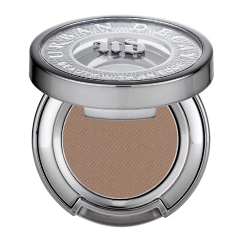 Ein kleiner runder Make-up-Deckel mit beigem Puder und Silberdeckel, leicht geöffnet.