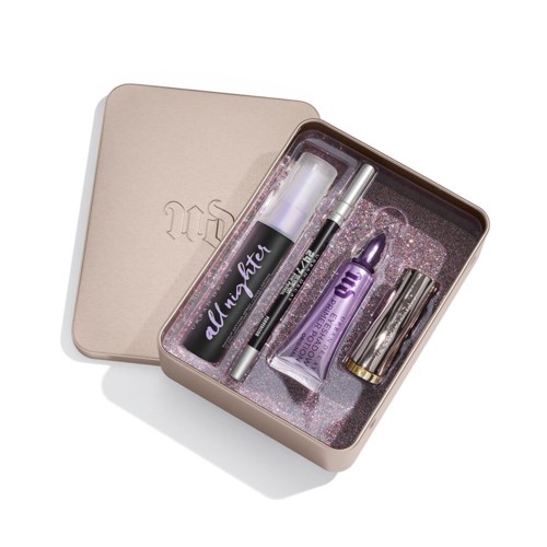 A cosmetic set in a beige box includes a black mascara, purple lipstick, eyeliner, and a lipstick base.