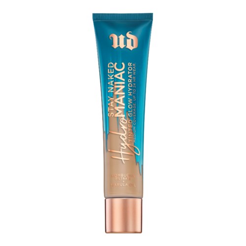 En tube af hudplejeprodukt i blå, fersken og guld, mærket 'Stay Naked Hydro Matic Foundation'.