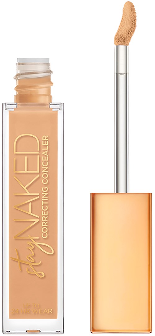 En concealer-flaska med beige flytande och en applikator, märkt 'Stay Naked Correcting Concealer', guldfärgad och genomskinlig förpackning.
