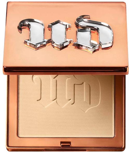 A makeup compact with a rose gold lid, featuring the word 'Dior' in shiny chrome letters. Inside, light-colored powder.