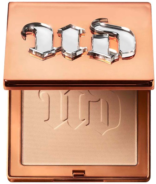 A makeup compact with a metallic lid displaying the brand logo, and a pressed powder inside.