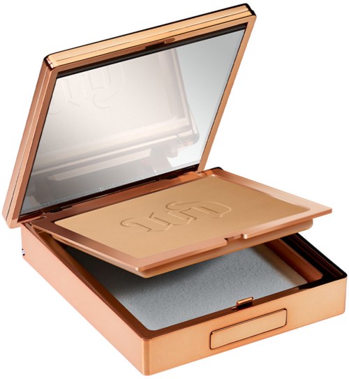 A makeup compact with a mirror and a pressed powder inside, under a rose gold case.