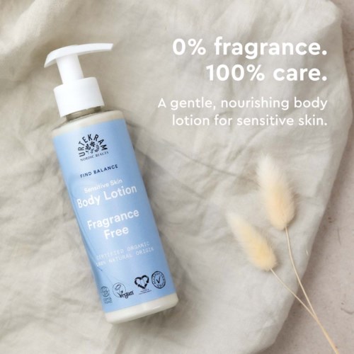 A blue bottle of gentle, fragrance-free body lotion on soft fabric, with two fluffy cotton stems nearby.
