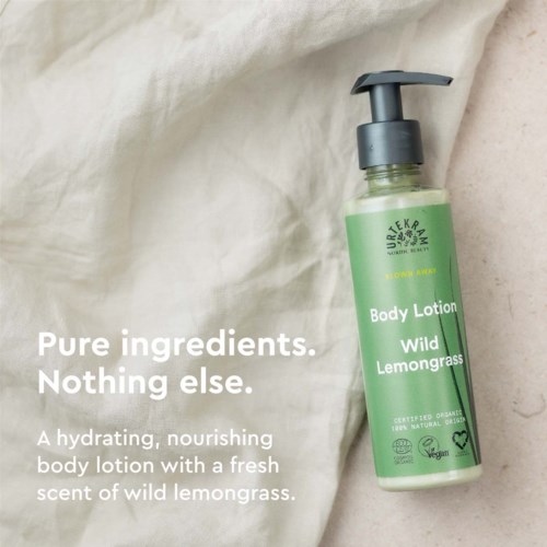 Zielona butelka balsamu do ciała z czarną pompką, oznaczona 'Wild Lemongrass', na jasnym tle z tkaniny.