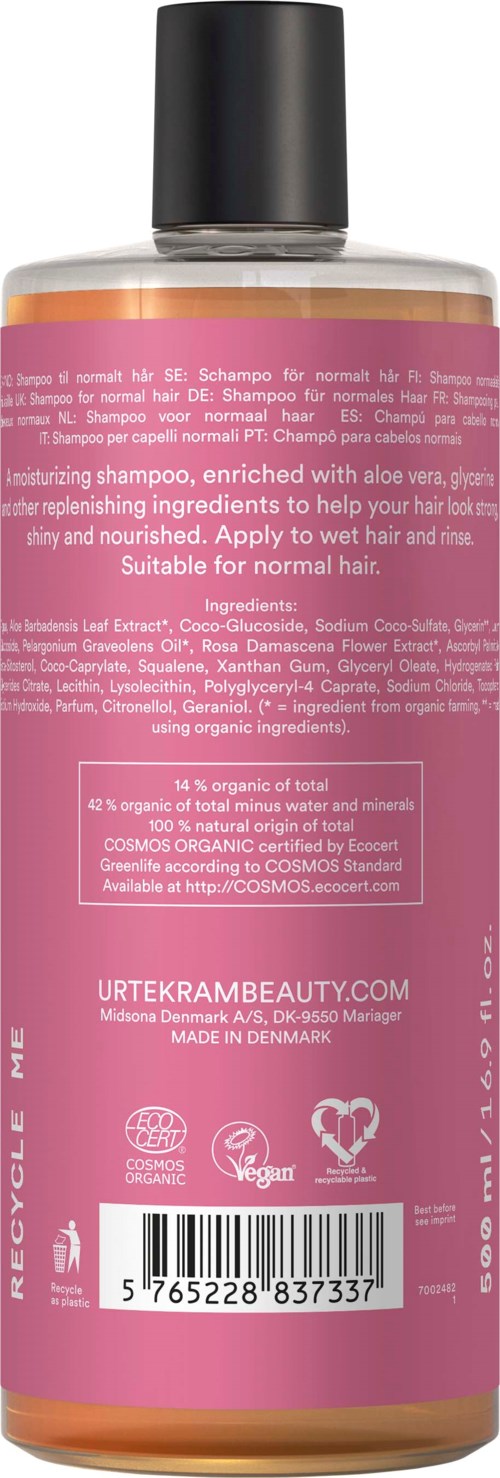 Een fles shampoo met een roze label met ingrediënten en merkgegevens.
