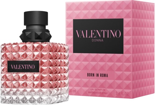 En rosa, texturerad parf bottle med svart lock och en matchande rosa förpackning med svart och rosa etikett.