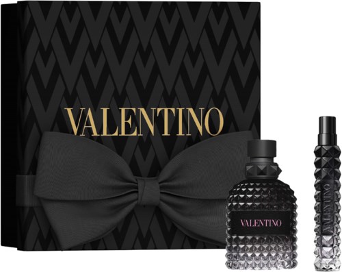Black gift box with a large bow and Valentino perfume bottles in front, gold Valentino logo on the box.