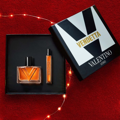 Vendetta Valentino Uomo Parfümflasche und Probe-Stick in einer schwarzen Schachtel auf rotem Hintergrund mit Lichterkette.