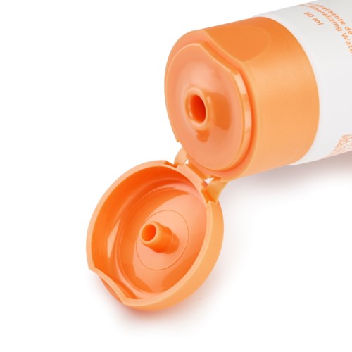 Bildet visar en orange och vit tub med öppen lock, troligen ett lotion- eller krämbehållare.