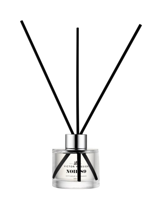 A glass diffuser with three black sticks protruding, labeled Victor Vincenz, designed for home scenting.