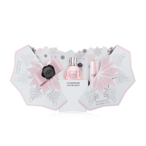 Ett parfumssett med en rosa parfymflaska, en liten rosa spray och svarta och rosa dekorativa föremål på papper med snöflingor och lövdesign.