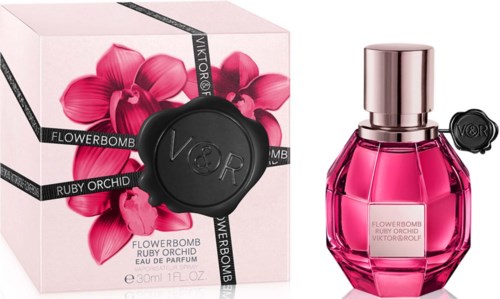 A pink perfume bottle with a silver cap and a box with pink flowers and a black seal.