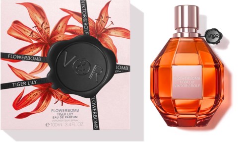 A perfume bottle with a bright orange color and a decorative box featuring lilies and a black seal.