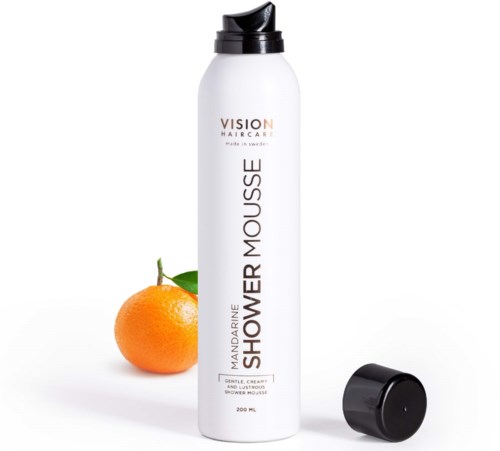 En vit flaska med svart lock, märkt 'Mandarine Shower Mousse,' med en apelsin bredvid.