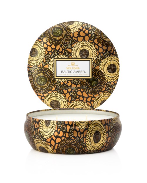 Decoratieve kaars met zwart en oranje bloemendecoratie op deksel en voet, labelt "Baltic Amber."
