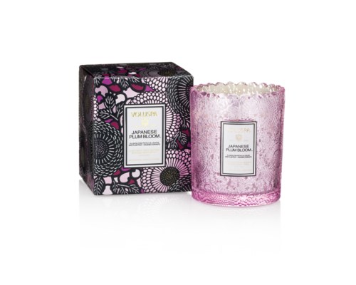 Ett rosa doftljus i glasbehållare med kristallliknande design och en svart blomsterlåda märkt "Japanese Plum Bloom."