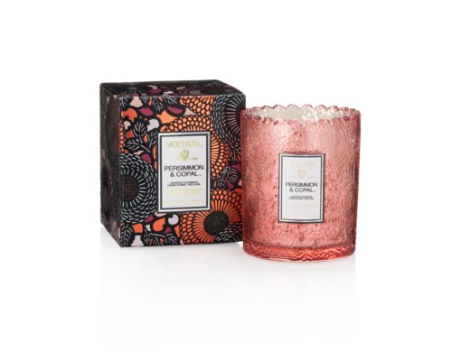 Ett rosa texturerat ljus i ett glas med en dekorativ låda. Boxen har blommönster i svart, orange, rosa och vitt.