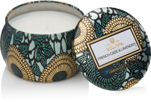 Een decoratieve kaars in een ronde container met zwart, geel en groen bloemenpatroon, gelabeld "French Cade & Lavender."