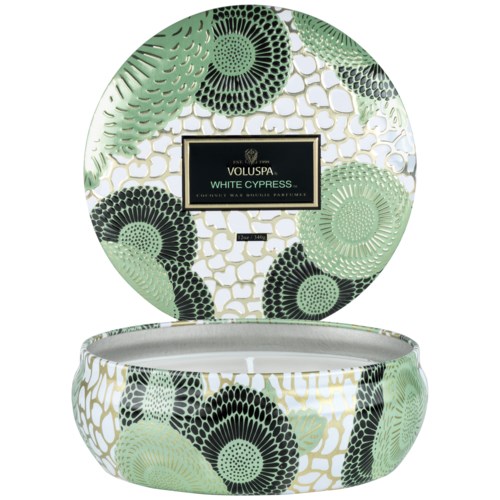En runt presentförpackningslåda med gröna och svarta blomstermönster och en svart etikett med texten 'Voluspa White Cypress.'