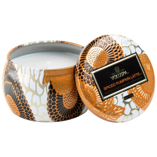 En rund behållare med lock, dekorerad med orange, svart och vitt floralmönster. Den innehåller ett doftljus.