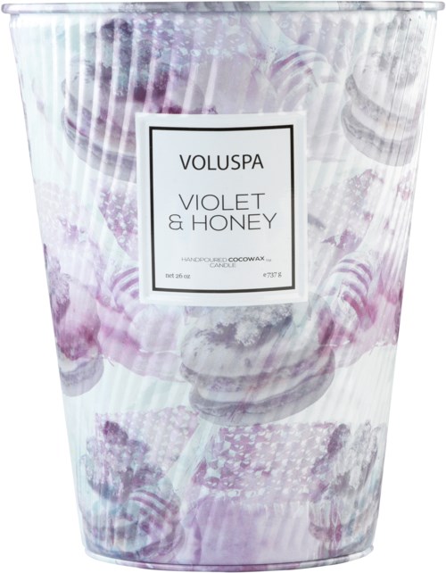 Ett tydligt plastljusbehållare med en vit etikett. Etiketten säger 'Voluspa Violet & Honey,' vilket anger doften.