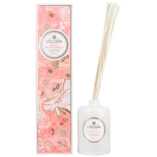 Een doos met roze bloemenprint en een witte fles met stokjes erin, waarschijnlijk voor geur of wierook.