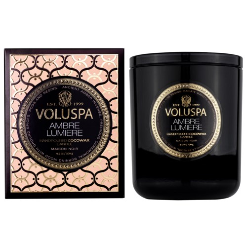 Two candles, one in a decorative box and one in a black jar, both labeled Voluspa Ambre Lumiere.