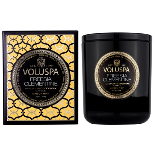 En svart ljusbox med gul blommönster och en svart ljusglas med en guld- och svart etikett.