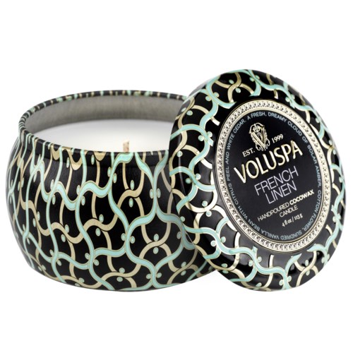 Dekorativt lys med svart, hvitt og teal svingemønster, merket "Voluspa French Linen."