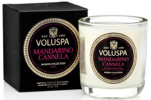 Et duftlys i en klar glasskrukke med en etikett som sier mandarin og kanel duft. Det står i en svart eske.